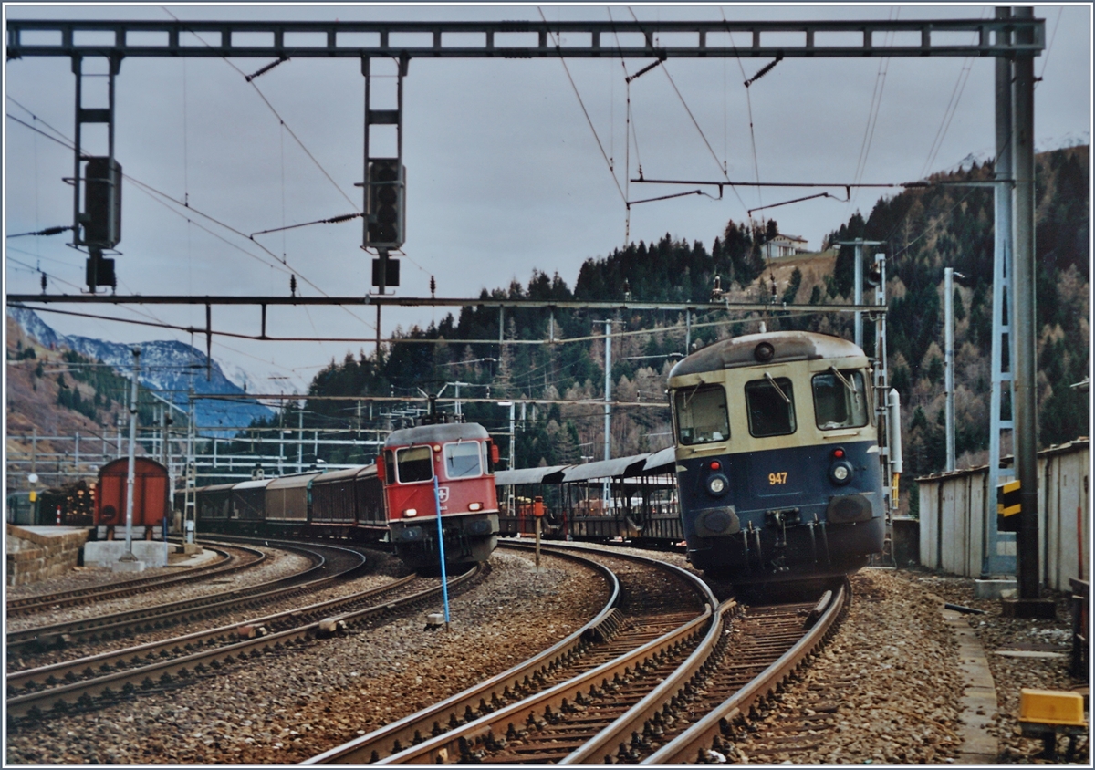 BLS Autoverlad Göschenen - Airolo. Lange Jahre, bis zu Eröffnung des Gotthard Strassentunnels 1981 betrieben die SBB einen Autoverlad durch den Gotthardtunnel. Als dann im Herbst 2001 nach einem Unfall den Strassentunnel für gut zwei Monate gesperrt werden musste, zog die BLS einen Autoverlad auf. 
Während der BLS Autozug in Airolo mit dem Steuerwagen 947 auf die Abfahrt Richtung Göschenen wartet, fährt eine  Re 10/10  durch.. 
Analogbilder vom 16. bzw. 21. November 2001 