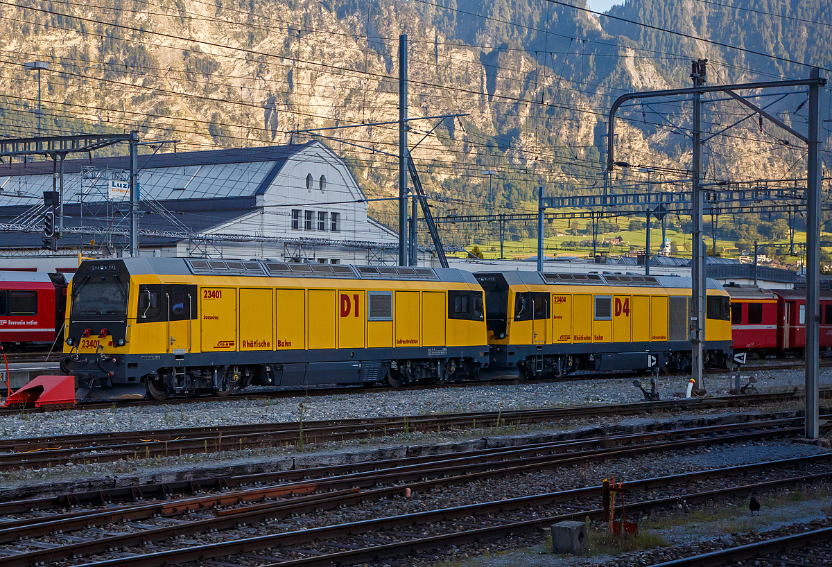 Die RhB Gmf 4/4 23401 „Surselva“ (D1), ex Gmf 4/4 28701, gekuppelt mit der RhB Gmf 4/4 23404 „Bernina“ (D4), ex Gmf 4/4 28704, vierachsige dieselelektrische Universallokomotiven der RhB Infrastruktur, sind am 05.09.2021 beim Bahnhof Landquart abgestellt. Aufgenommen aus dem Zug heraus. 

Vier dieser vierachsigen meterspurigen dieselelektrischen Loks wurde 2013 von Schalker Eisenhütte Maschinenfabrik GmbH in Gelsenkirchen  unter den Fabriknummern 2585 bis 2588 als Gmf 4/4 28 701 bis 28 704 für die RhB gebaut, 2015 wurde sie in Gmf 4/4 23401 bis 23404 um bezeichnet.

Die vierachsige dieselelektrische Lokomotive Gmf 4/4 II (234..) ist eine besondere Entwicklung von Schalke für den Bereich „Infrastruktur“ der Rhätischen Bahn (RhB) in der Schweiz. 

Um im gesamten RhB-Netz einschließlich der Berninabahn eingesetzt werden zu können, zählten zu den Voraussetzungen die Lauffähigkeit in Bögen ab 45 m Radius und Neigungen bis 70 ‰, die Einhaltung einer maximalen Radsatzlast von 16 t, sowie ein kleines Lichtraumprofil (Tunnelprofil). Außerdem ist die Lokomotive auch unter extremen klimatischen Bedingungen zuverlässig einsatzfähig, ihr Einsatzbereich reicht von -35°C bis +40°C, auch bei feinkristallinem Schnee ist sie fahrbereit.
Die Umsetzung dieser technischen Herausforderungen wurde vereint mit der Integration einer Vielzahl spezifischer Komponenten. So verfügt die Lokomotive unter anderem über vier verschiedene Bremssysteme, eine Mehrtraktionsfähigkeit von bis zu drei Lokomotiven, zudem sind sie mit Funkfernsteuerung ausgerüstet. Die Höchstgeschwindigkeit beträgt 100 km/h, die Lokomotiven können jedoch auch bei niedrigen Dauergeschwindigkeiten mit Schneepflügen oder Gleisbauzügen eingesetzt werden. Auch die offizielle Betriebsbewilligung des Schweizer Bundesamts für Verkehr (BAV) macht sie auf dem Markt für Diesellokomotiven einzigartig.

Ihr Haupteinsatzzweck ist der Transport von schweren Bau- oder Spezialzügen auch bei abgeschaltetem Fahrdraht, der Betrieb von Schneefräsen im Winter, das Abschleppen von havarierten Zügen und das Rangieren in den Bahnmeisterbezirken.

Der Lokkasten wurde bei der FTD Fahrzeugtechnik Bahnen Dessau in Stahlleichtbauweise geschweißt mit angeklebten GFK-Fronten und Seitenwänden aus Aluminiumwabenplatten. 

Mit der Entwicklung der Drehgestelle beauftragte die Schalker Eisenhütte Maschinenfabrik GmbH das schweizerische Ingenieurbüro PROSE in Winterthur. Aufgrund der geringen Stückzahl von nur vier Lokomotiven wurde auf die Entwicklung spezieller Fahrmotoren verzichtet, zum Einsatz kommen Antriebe aus dem Asiarunner von Siemens Rail Systems. Die Aufhängung der Motoren erfolgt mittels Tatzlager-Antrieb.

Die Primärfederung erfolgt über Lemniskatenlenker, die somit robuste Konstruktion berücksichtigt die harten Einsatzbedingungen, auf radiale Einstellbarkeit wird verzichtet.

Besonders hohe Sekundärfedern mit speziellen Gummi-Kipp-Elementen tragen den anspruchsvollen Einsatzbedingungen mit sehr kleinen Kurvenradien Rechnung. Daraus resultiert ein geringer Ausdrehwiderstand auch in engen Bögen (kleinster befahrbarer Bogen: 42m). Für stabiles Fahrverhalten bei hohen Geschwindigkeiten auf der Geraden sind bei dem geringen Ausdrehwiderstand Schlingerdämpfer nötig. Von den Sekundärfedern gibt es je Drehgestell 4 Paare, wobei ein Paar aus innerer und äußerer Feder besteht. Die Zugkraft wird drehzapfenlos über Zug-/Druck-Stange an den Lokkasten übertragen. Besonders ist hierbei die doppelte Kröpfung. Nötig ist diese um trotz der großen Auslenkungen ausreichend Abstand zu anderen Bauteilen des Drehgestells zu halten.

Als Besonderheit ist die Materialwahl zu sehen: Um dem angestrebten Winterdienst Rechnung zu tragen ist ein Stahl mit hoher Duktilität bei niedrigen Temperaturen gewählt worden.

Neben dem MTU-Motor ist ein 37 Kilowatt-Hilfsdiesel mit Generator installiert. Bei stehender Lok sorgt er für die Bordstromversorgung bei abgeschaltetem Hauptdiesel sowie die Versorgung von externen elektrischen Anlagen oder Arbeitsgeräten an Baustellen.

Der Auftragswert für die vier dieselelektrische Universallokomotive Gmf 4/4 betrug rund 25 Millionen Franken.

Technische Daten der Gmf 4/4 :
Hersteller: Schalker Eisenhütte Maschinenfabrik GmbH
Hersteller Typenbezeichnung: RDE1800-D064-1000-2586/2013-CH
Anzahl: 4
Baujahr: 2013
Spurweite:  1.000 mm
Achsanordnung:  Bo’Bo’
Länge über Puffer:  16.690 mm
Drehzapfenabstand (theoretisch): 9.800 mm
Radsatzstand im Drehgestell: 2.300 mm
Breite:  2.650 mm
Höhe:  3.885 mm
Treibraddurchmesser: 1.070 mm (neu)
Motor:  V 12-Zylinder-Dieselmotor  vom Typ MTU 12V 4000 R43L (Stage III b)
Antrieb: dieselelektrisch
Antriebsstrang:  Wechselstromtechnik (AC)
Gewicht:  64 t
Leistung:  1.800 kW
Max. Geschwindigkeit: 100 km/h
Tankinhalt: 2.500 l
Max. Anfahrtszugkraft: 230 kN
Dauerzugkraft: 160 kN
Kleinster bef. Halbmesser: 40 m
Max. Anhängelast (Doppeltraktion) bei 70‰: 140 t
Max. Anhängelast (Doppeltraktion) bei 25‰:  420 t
