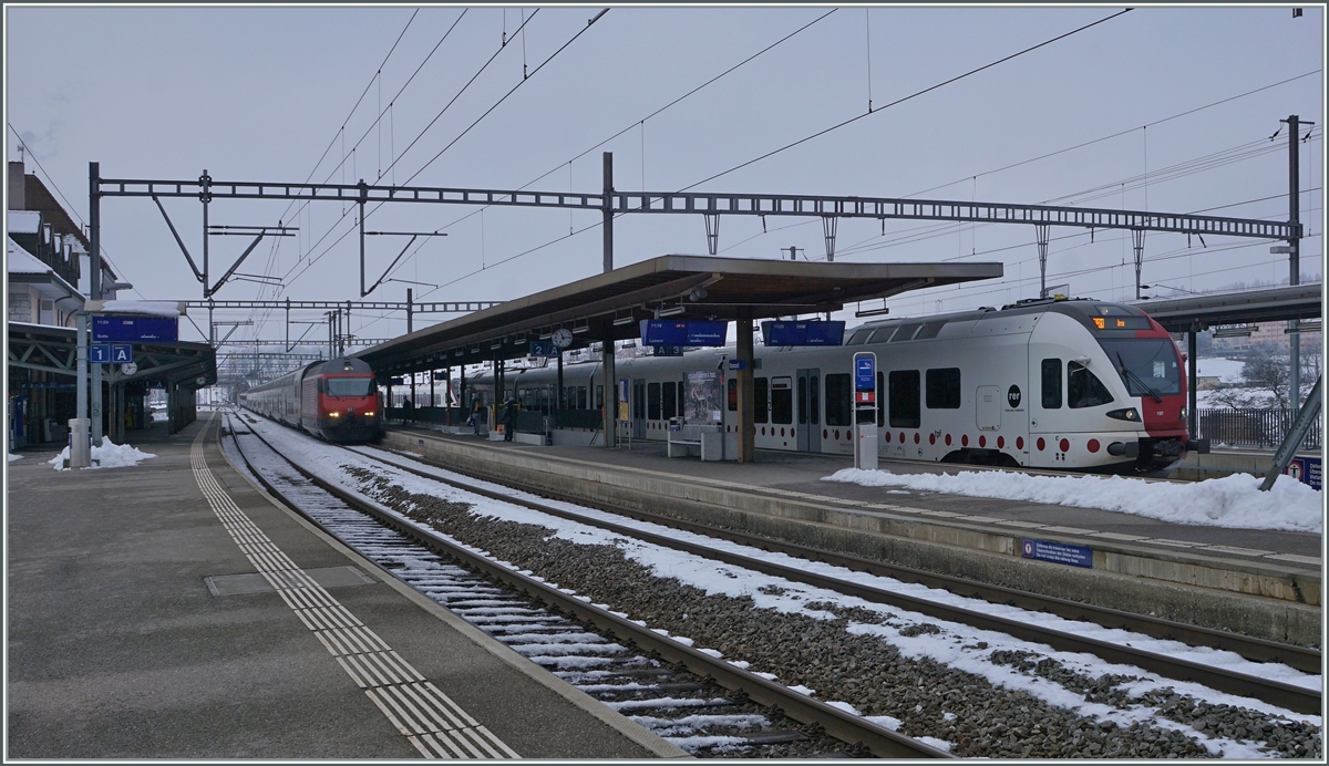 Während in Romont ein TPF RABe 527 auf die Abfahrt nach Ins wartet nähert sich eine SBB Re 460 mit ihrem IR 15 nach Luzern. 

22. Dez 2021 