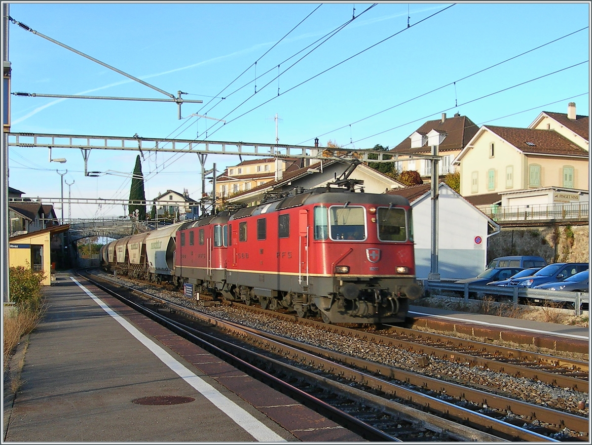 Zwei SBB Re 4/4 II fahren mit einem  Spaghetti -Zug in Rivaz durch, der Güterschuppen ist verschwunden und die Gleisanlage reduziert worden, immerhin besteht noch mitten im Bahnhof und damit betrieblich wenig ideal eine Gleisverbindung. 

19. Nov. 2006