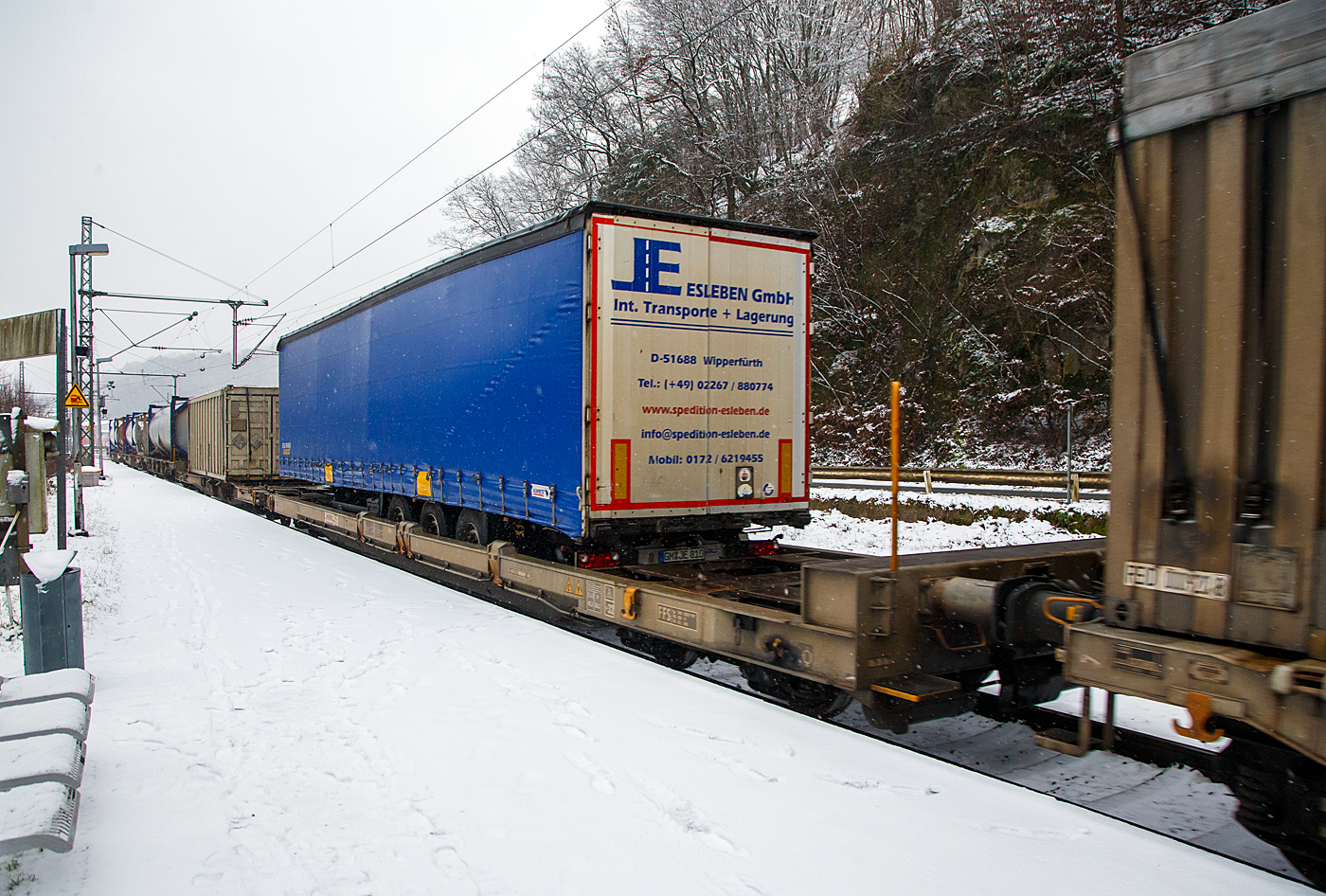 Achtachsiger niedrig gelegte Doppelwagen Jumbo II / Mega II (Trag-/Taschenwagen-Doppeleinheit) der Gattung Sdggmrrss, 83 85 493 3 329-5 CH-HUPAC, der Hupac Intermodal SA, am 19.01.2023 im Zugverband bei einer Zugdurchfahrt in Scheuerfeld (Sieg) in Richtung Köln.Hier beladen vorne mit einem Sattelzugauflieger und mit einem Container.

Diese Wageneinheiten bestehen aus einer niedrigen Tragwagenhälfte für Container und Wechselbehälter („CT“) und einer niedrigen Taschenwagenhälfte („SK“). Die beiden Wagenhälften sind mit einer, im Normalbetrieb nicht zu trennenden, (von den Waggons der RoLa, Saadkms 690, abgeleiteten) Kurzkupplung verbunden.
