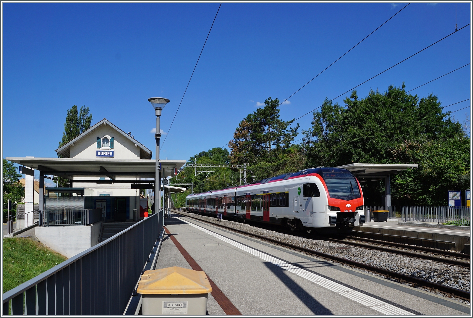 Während zei SBB Flirt3 RABe 523.1 auf Gleis 2 in Burier halten, zeigt sie links im Bild die wenige Überzeugende Normgestaltung kleinerer Station in Burier, welche die Sicht auf das Gebäude verhindert und ein Fremdkörper im Bild darstellt.

30. Juli 2022